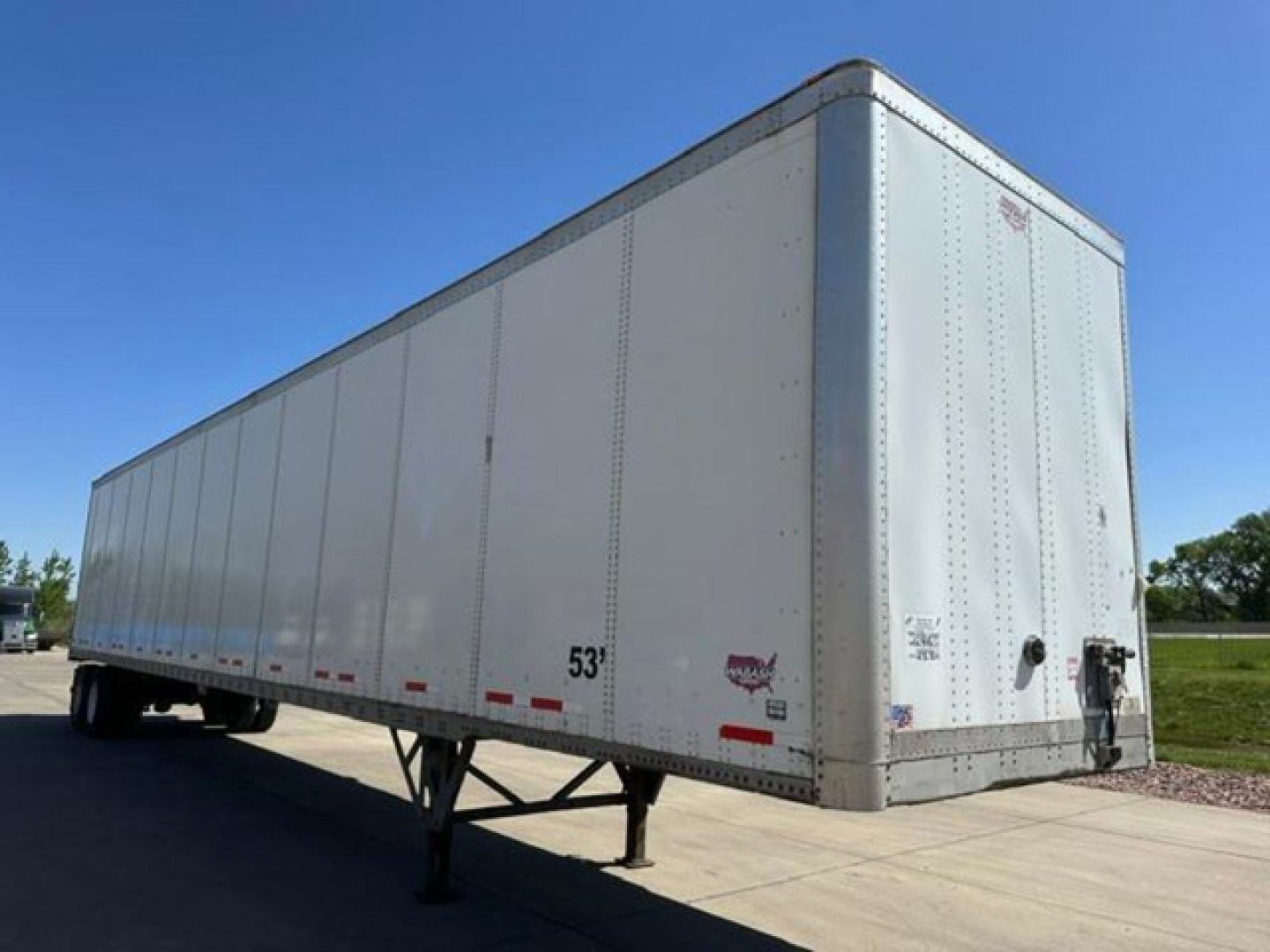 Trailer side and rear view of a 53' Wabash van trailer showing flat white aluminum panels and rear doors.