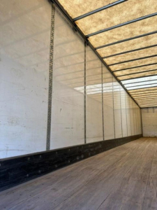 Trailer interior showing empty cargo area of a 2016 Wabash van with wooden floor and side rails.