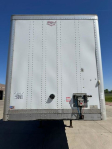 Rear view of a white 2016 Wabash van trailer with riveted metal panels, light reflector, and back door hardware visible.
