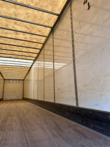 Trailer interior showing wooden floor and white sidewalls with vertical rails and load area in a Wabash van.