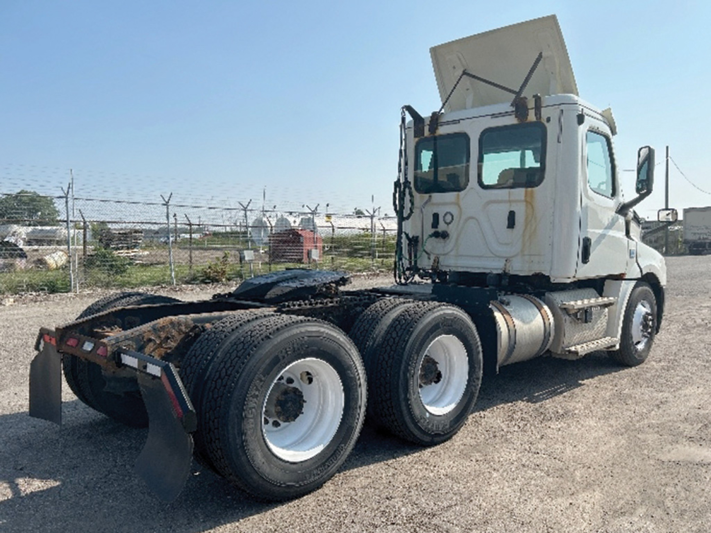 Truck chassis and cab of a 2019 Freightliner Cascadia126 daycab with dual rear axles and a raised hood, view from passenger side.