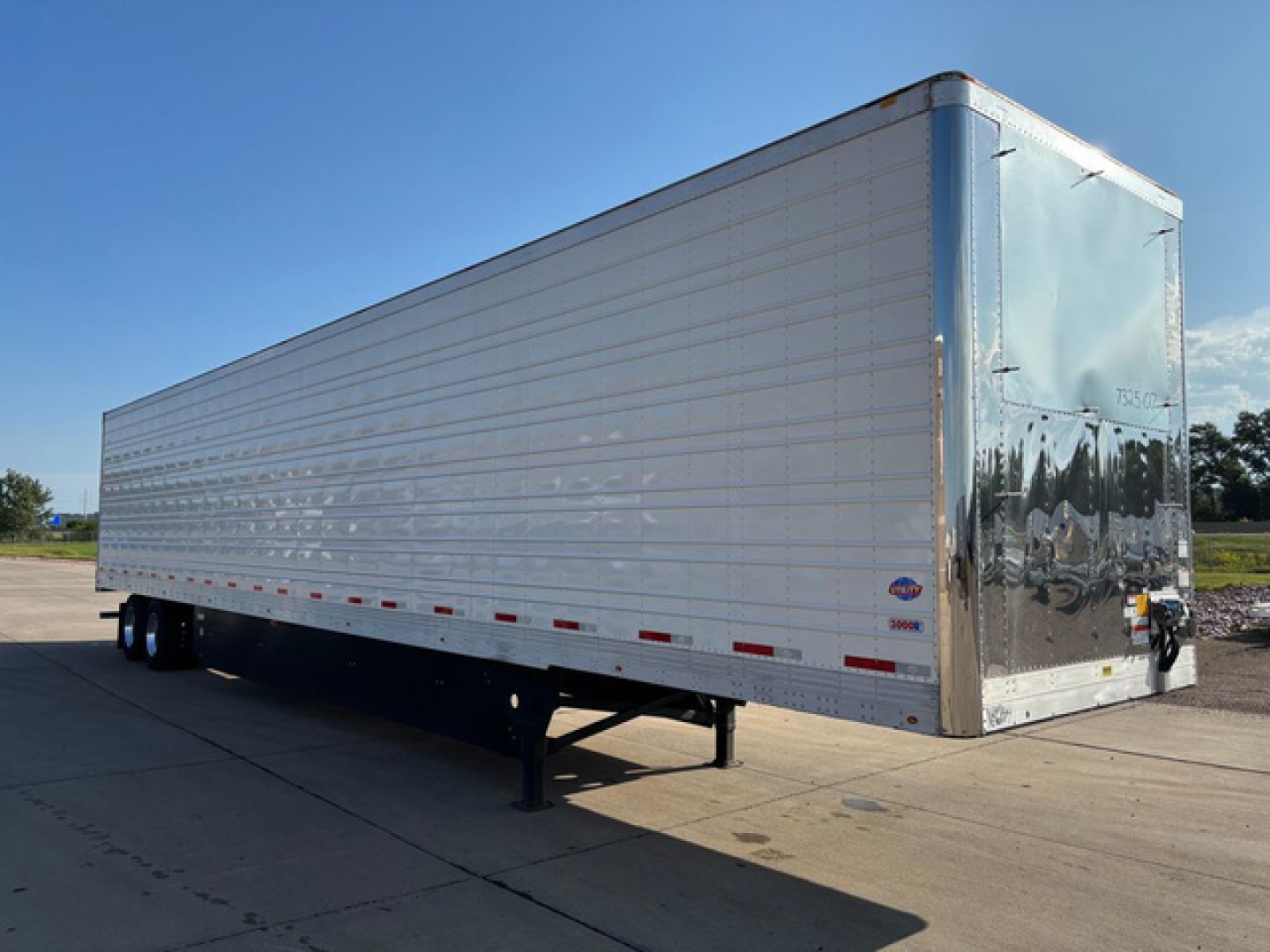 Trailer side and rear showing a new 2027 Utility Reefer refrigerated trailer with silver aluminum exterior, tandem axles, and raised landing gear.