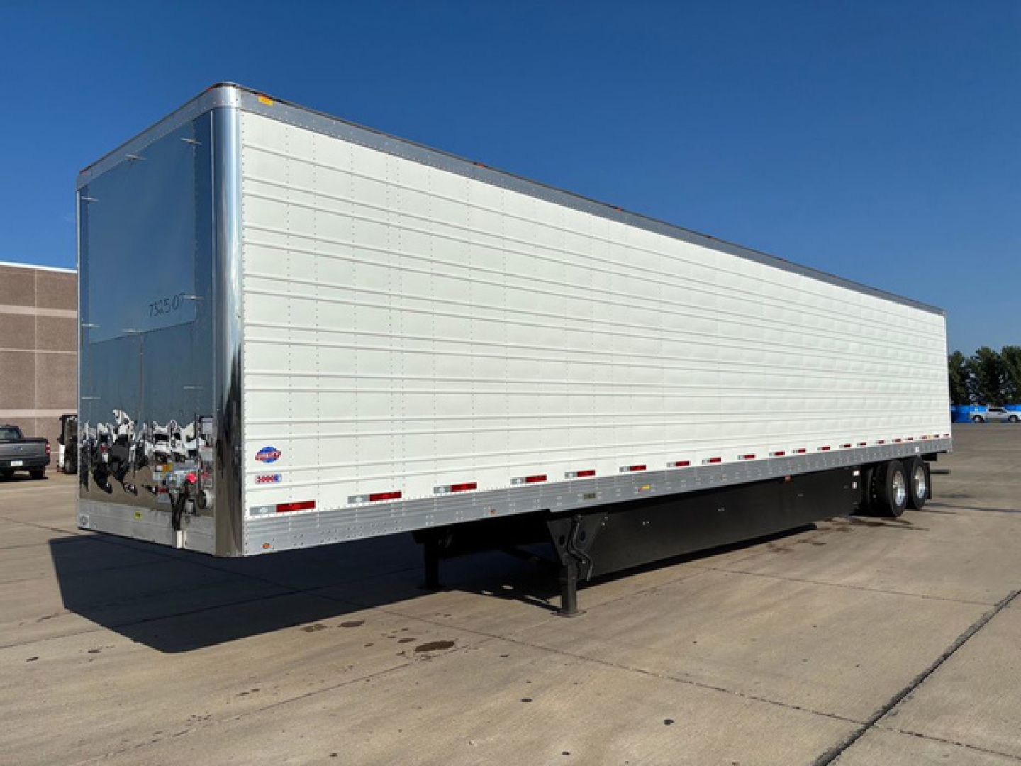 Utility reefer trailer showing white aluminum exterior and dual rear axles on a paved lot.