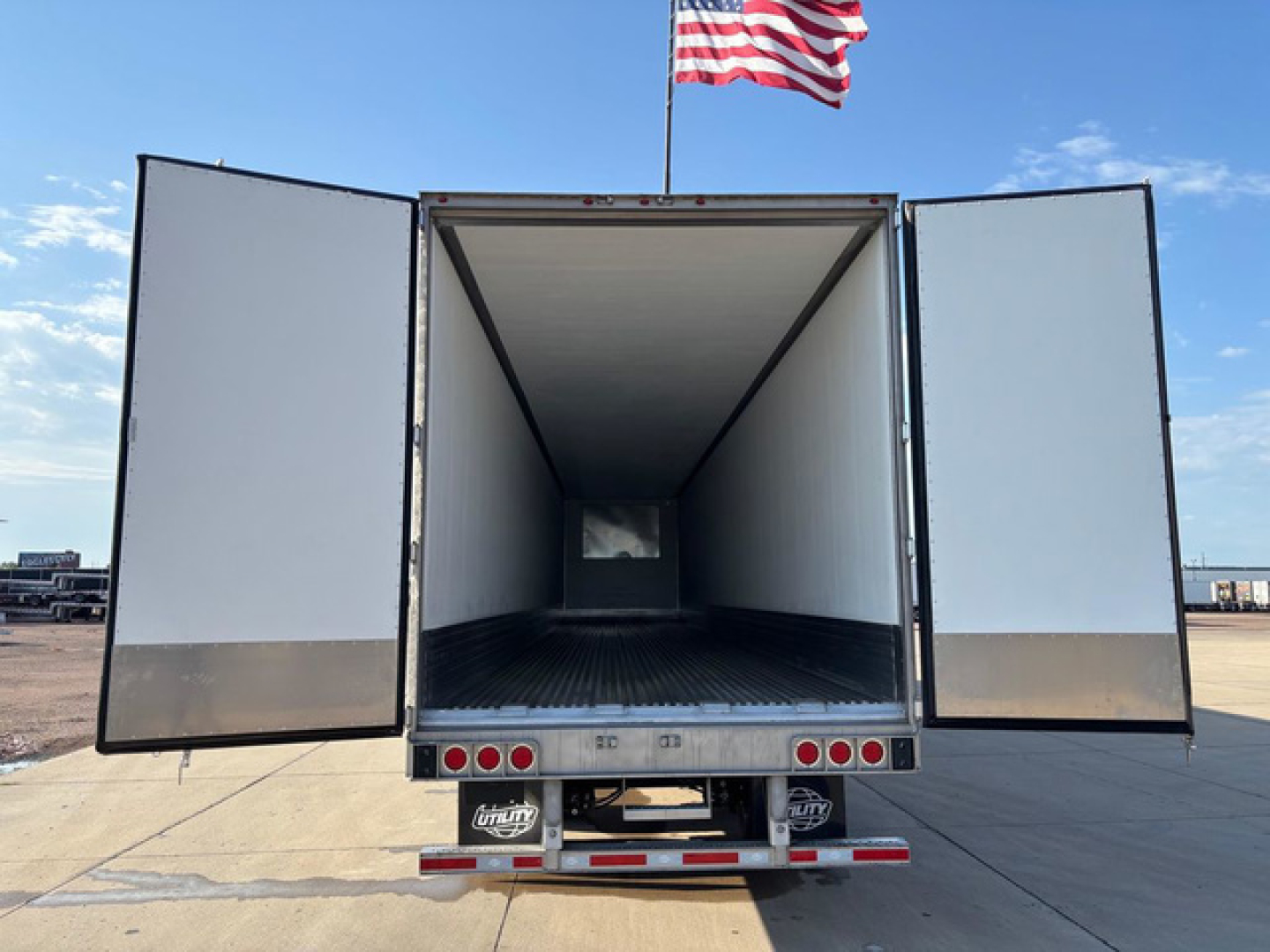 Utility reefer trailer with rear doors open showing empty cargo area and clear interior walls.