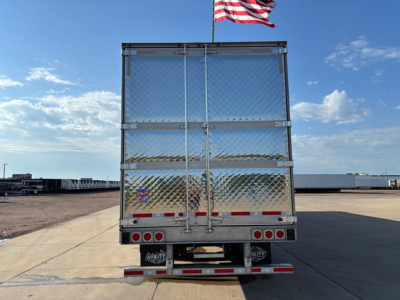 Rear view of a 2027 utility refrigerated trailer with diamond plate lower section and metal doors, red and white reflective tape, and an American flag on top.