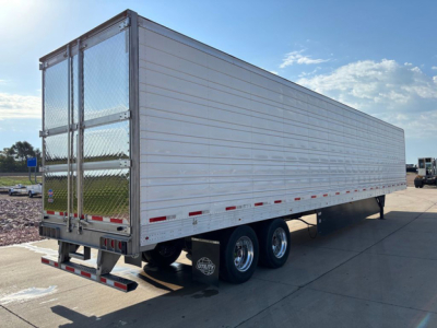 Trailer side view of a new 2027 Utility Reefer trailer showing dual rear doors, aluminum panels, tandem axles, and Utility logo mudflap.