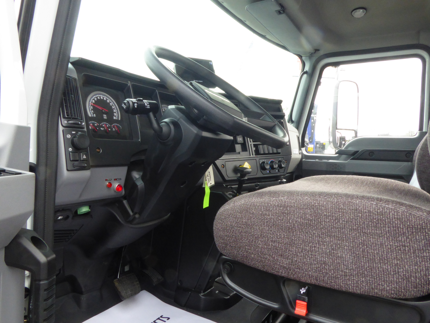 Interior of 2025 Mack MD7 cab showing steering wheel, dashboard gauges, and driver seat.