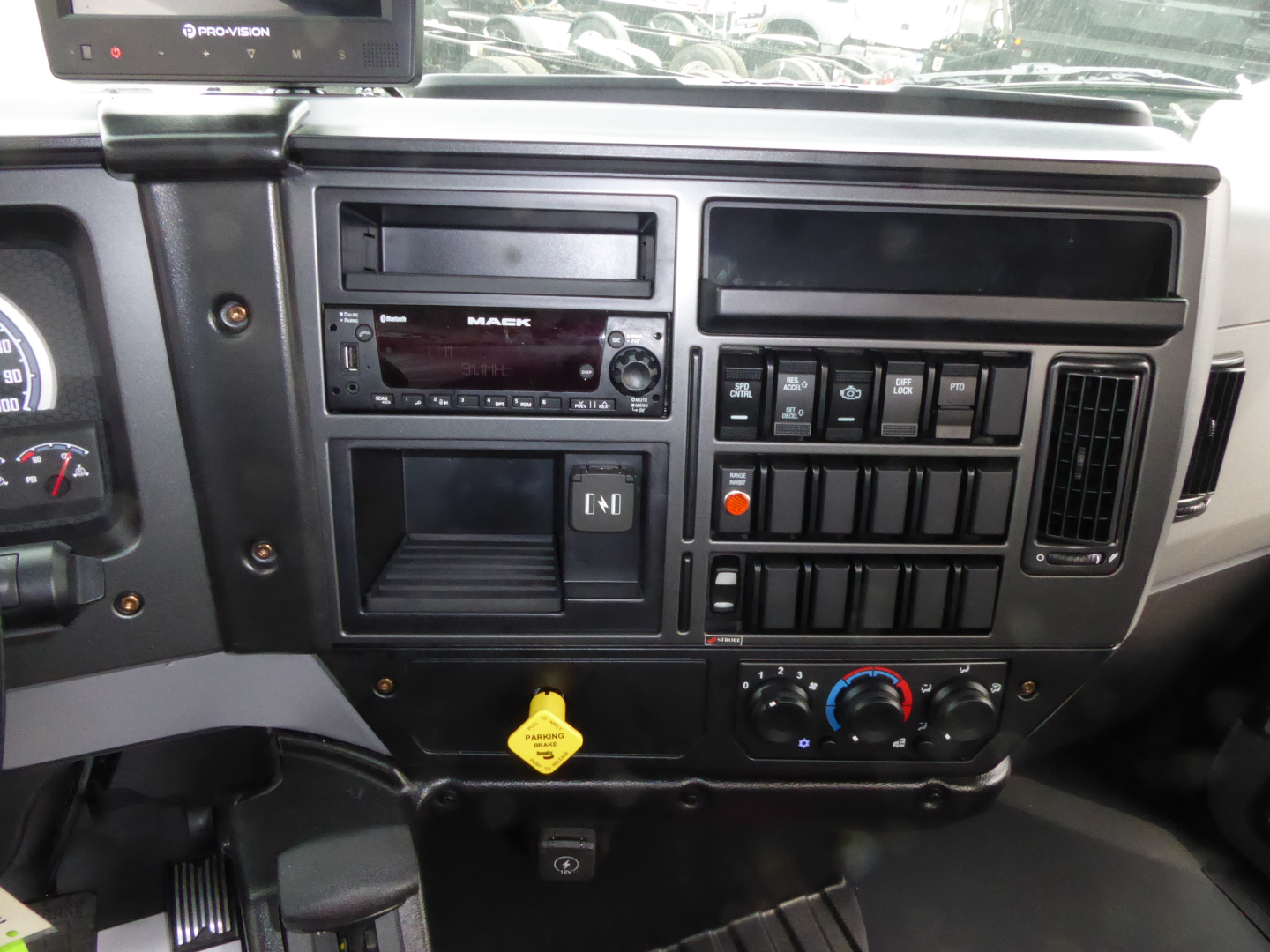 Dashboard and center console of a Mack MD7 truck showing radio, control switches, climate controls, and ignition area.
