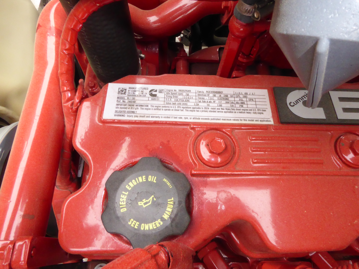 Mack MD7 engine bay showing diesel engine oil cap and label plate on red valve cover.