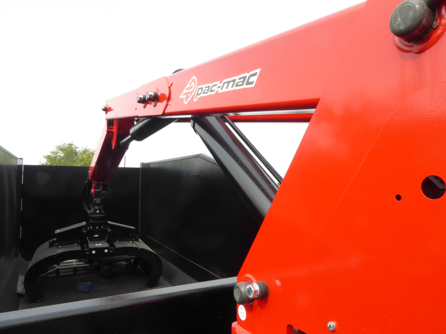 Mack MD7 grapple truck component showing Pac-Mac hydraulic arm and grapple attachment with red boom and black grapple mechanism.