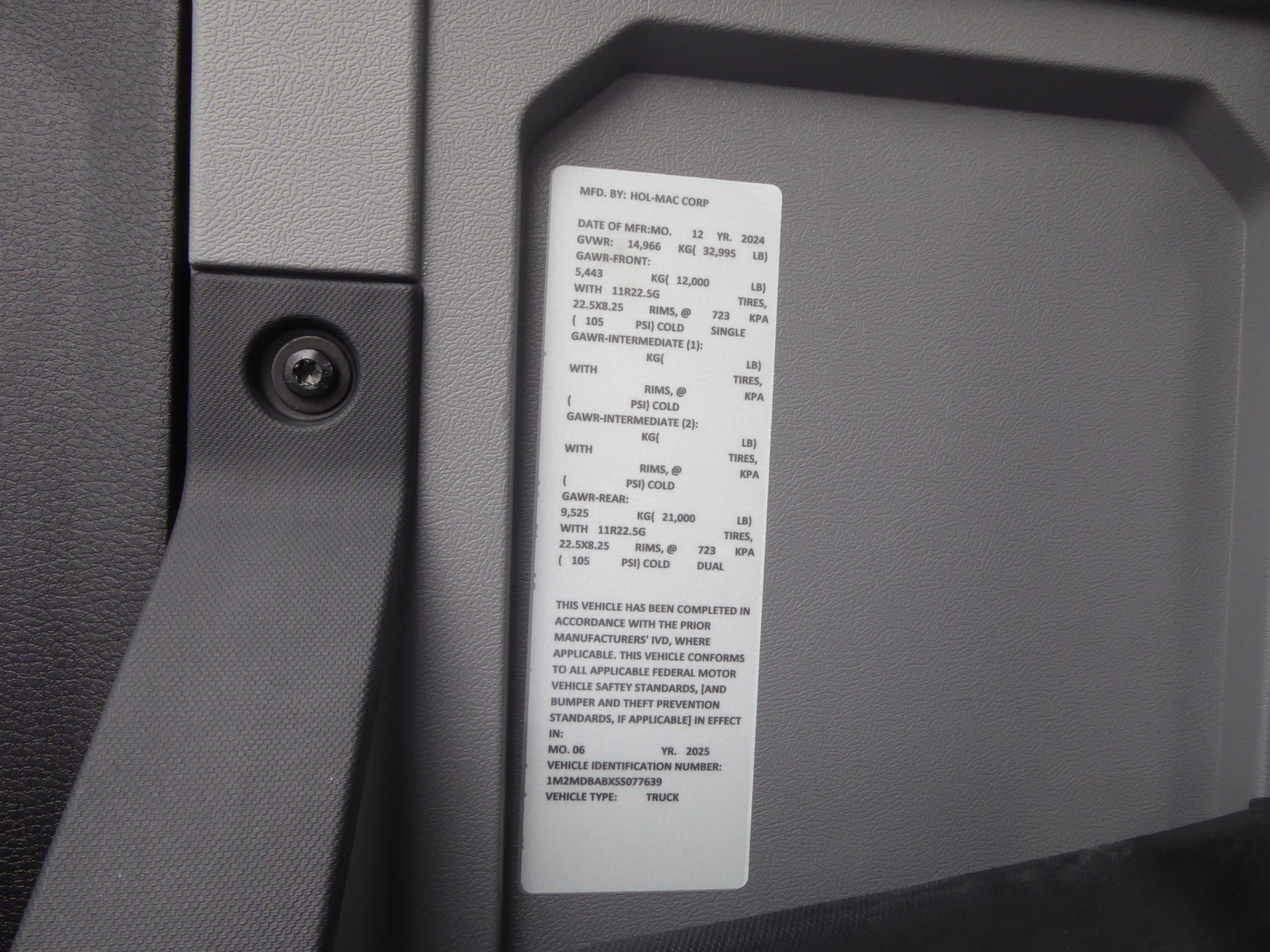 Vehicle data label on 2025 Mack MD7 truck cab area showing specifications and VIN label near latch.