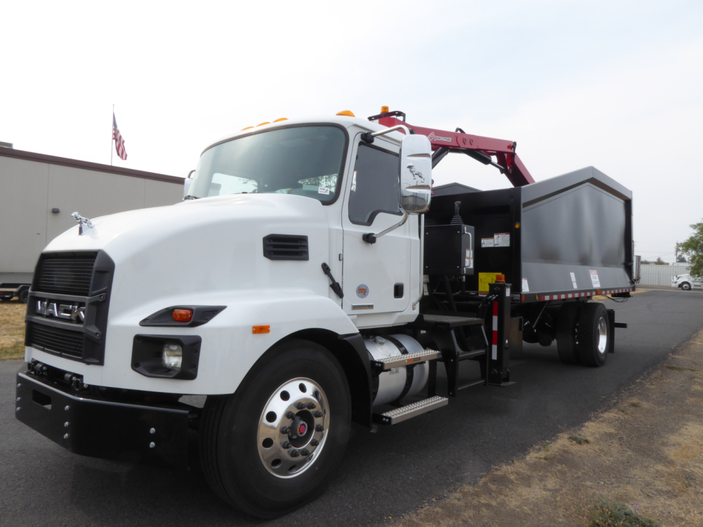 Mack MD7 truck in white with grapple arm and dumping hopper, side view showing front bumper, wheel, and branding.