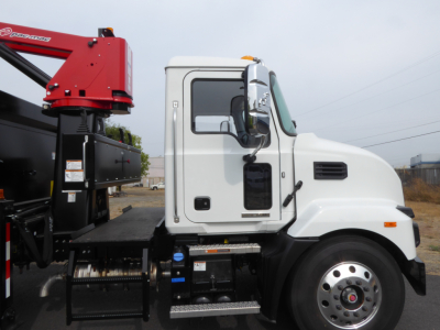 Truck side view showing white cab of a 2025 Mack MD7 grapple truck with red crane attachment and alloy wheels.