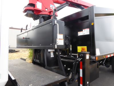 Truck bed with hydraulic grapple and control cabinet for a 2025 Mack MD7, side view showing equipment and hydraulic lines.