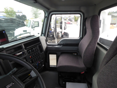 Truck cab interior of a 2025 Mack MD7 showing driver seat, steering wheel, and dashboard in view.