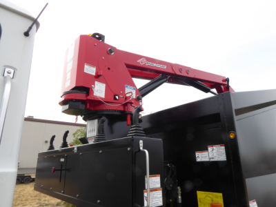 Truck with red crane arm mounted on a black dump body showing Pasfgeo or PassGIGE brand label and control levers.