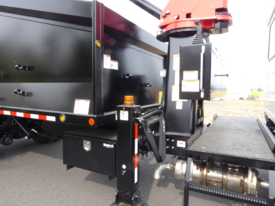 Mack MD7 truck with grapple equipment showing hydraulic system, black toolbox, and red grapple actuator on a flatbed truck.