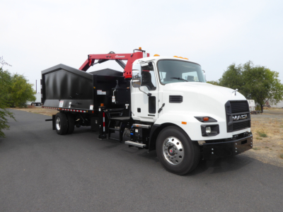 Mack MD7 truck with a grapple attachment viewed from the side, white cab, black dump bed, red hydraulic arm.