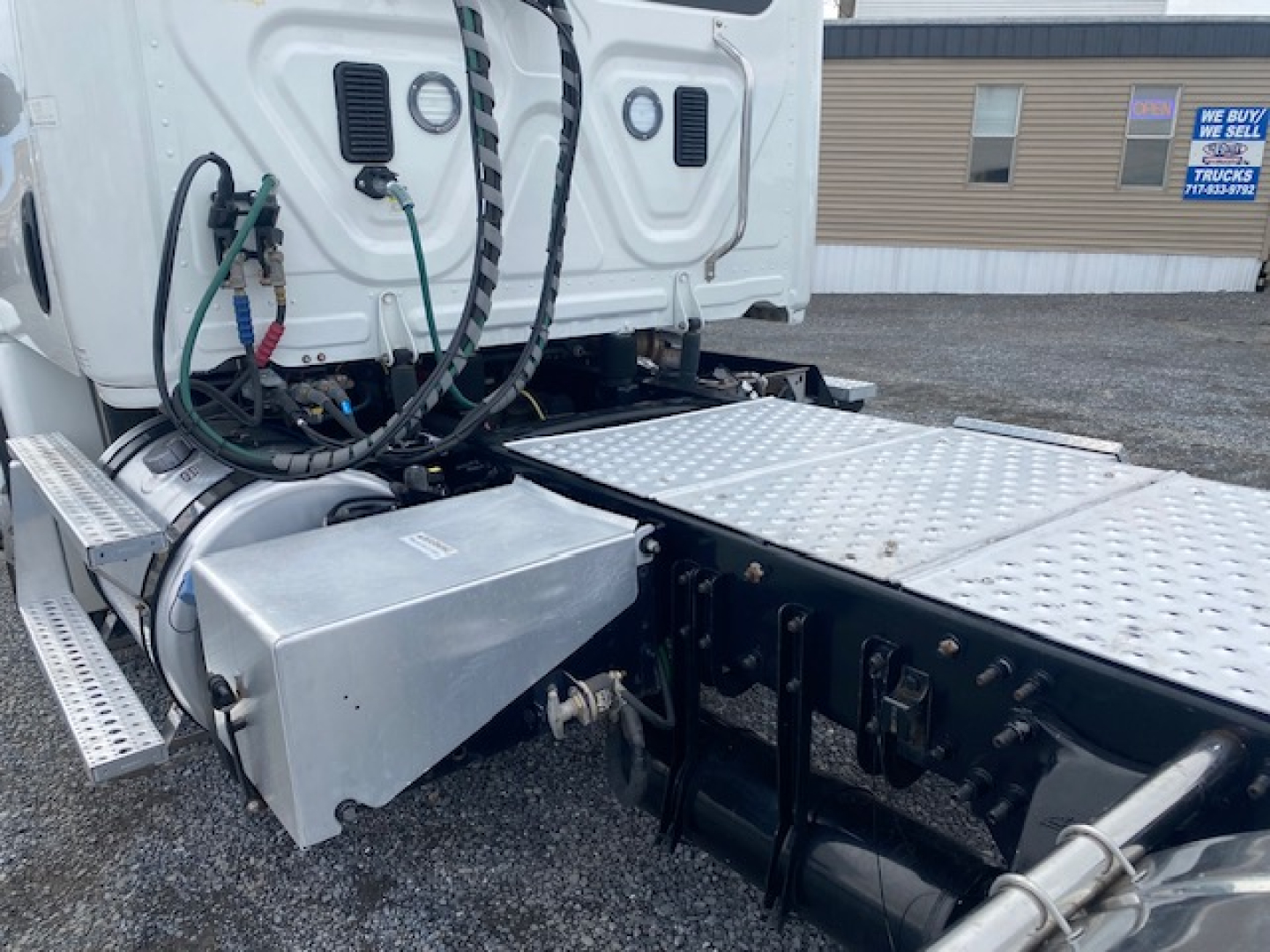 Freightliner Cascadia 113 cab with sideview showing fuel lines and metal toolbox on left rear, aluminum steps, and chassis area.