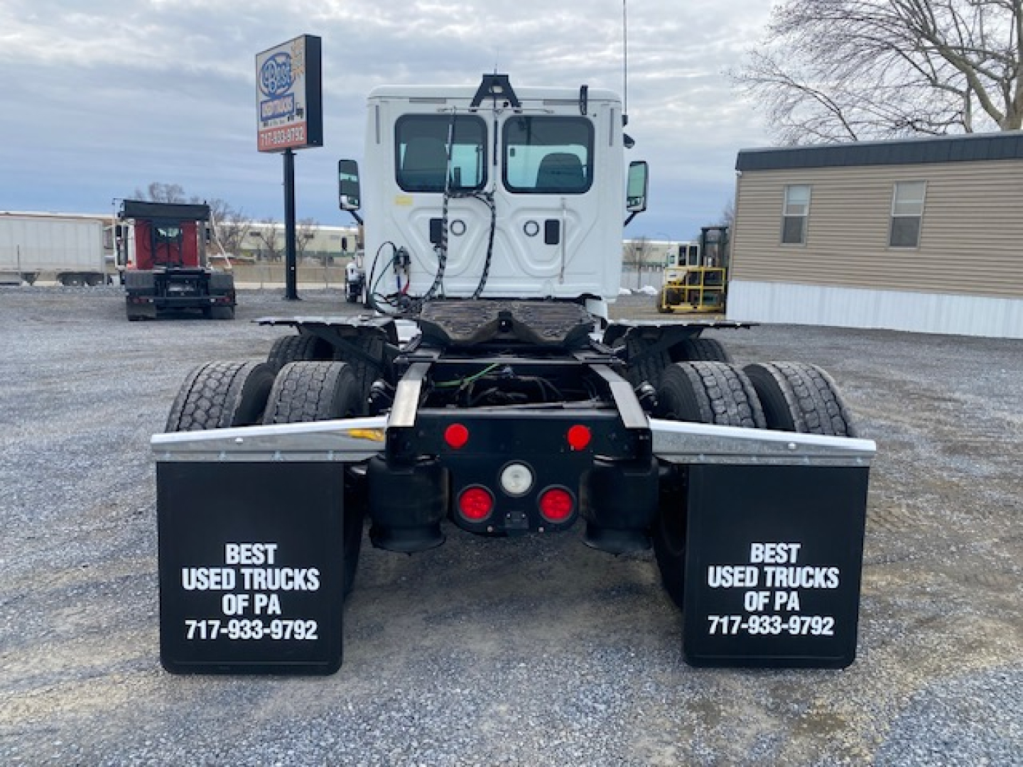 Rear view of a Freightliner Cascadia 113 tractor, with twin rear axles and black fenders displaying 'BEST USED TRUCKS OF PA' and contact number.