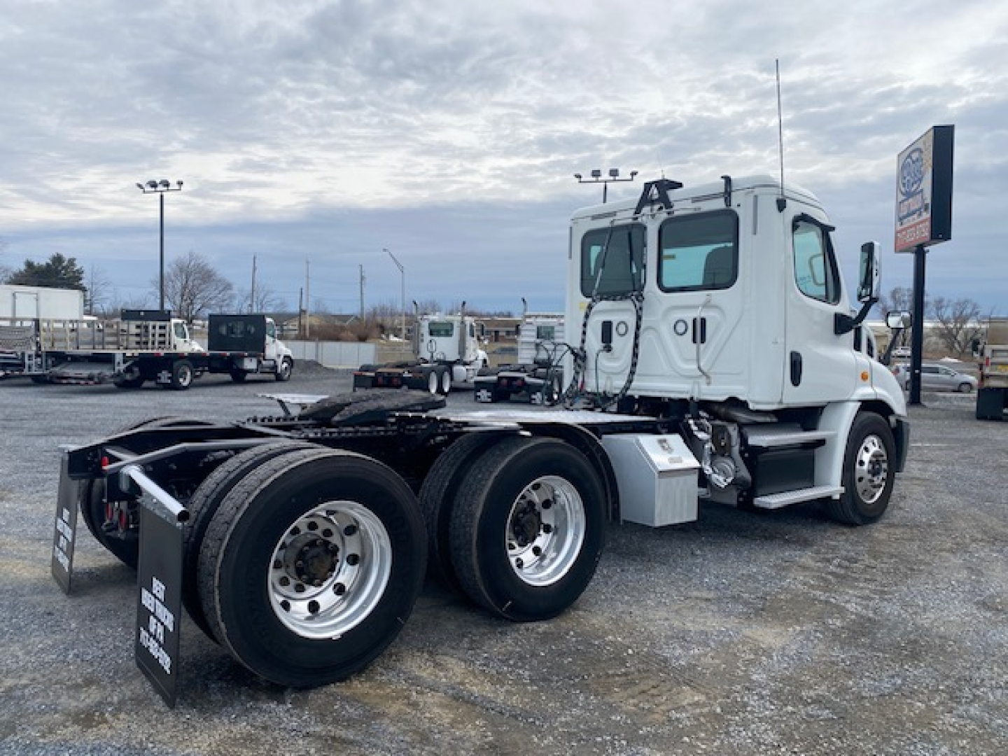 Conventional daycab truck chassis showing rear wheels and sleeper cab with Freightliner badge and VIN plate visible.