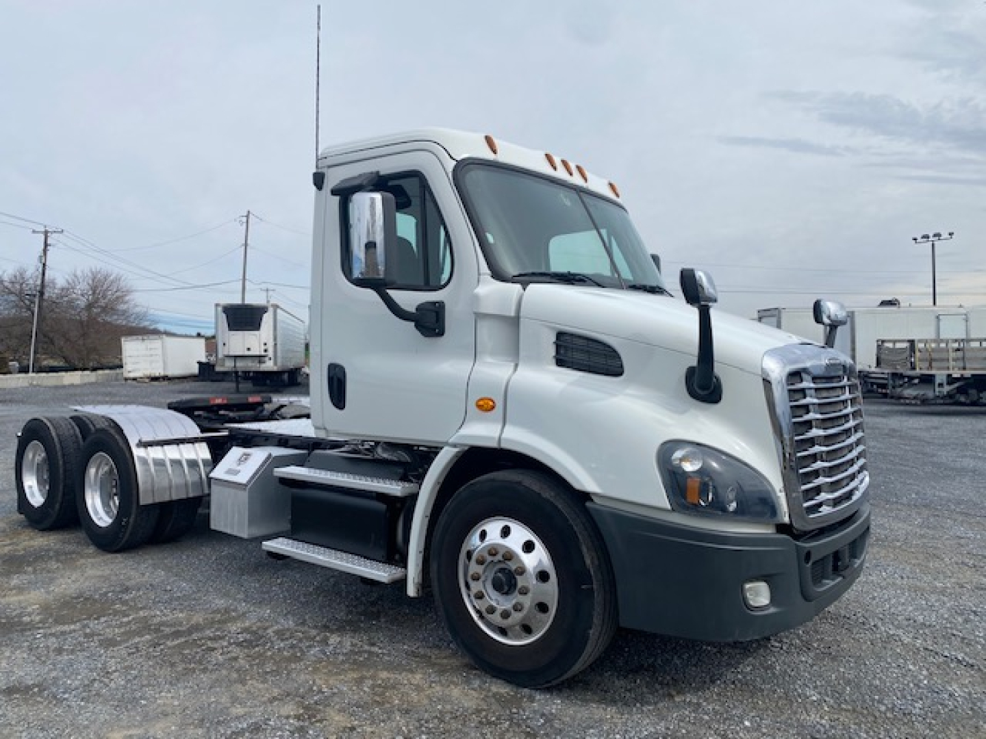 Freightliner Cascadia 113 day cab truck side view showing cab and chassis, with fuel tanks and wheels visible.