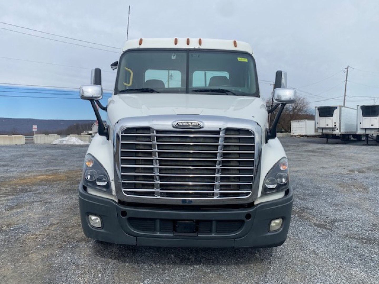 Freightliner Cascadia 113 front view showing chrome grille and bumper, headlights, windshield with mirrors.