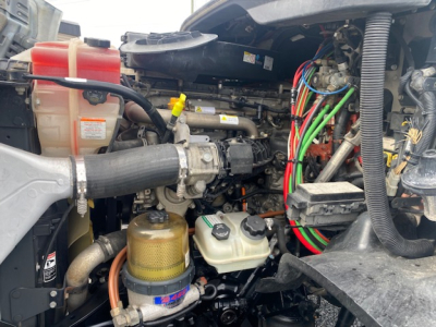 Cascadia diesel engine bay with coolant reservoir, power steering lines, and wiring harness visible.