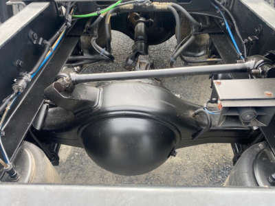 Rear view of a Freightliner Cascadia 113 chassis showing solid axles, differential housing, suspension links, and wiring harnesses in the engine bay area.