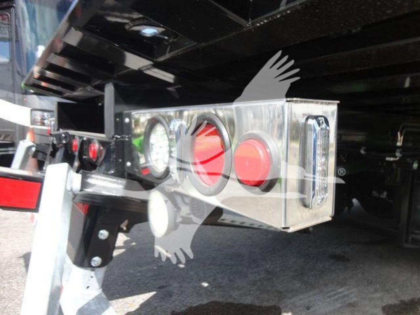 Swing-out bumper with chrome box and round taillights under the truck bed viewed from behind.