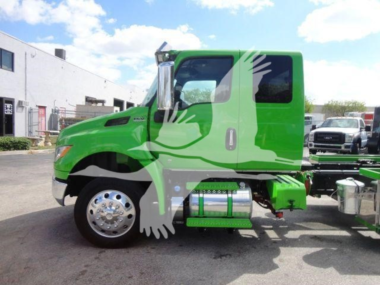 Green 2027 International MV truck cab side view showing stepside and chrome fuel tanks.