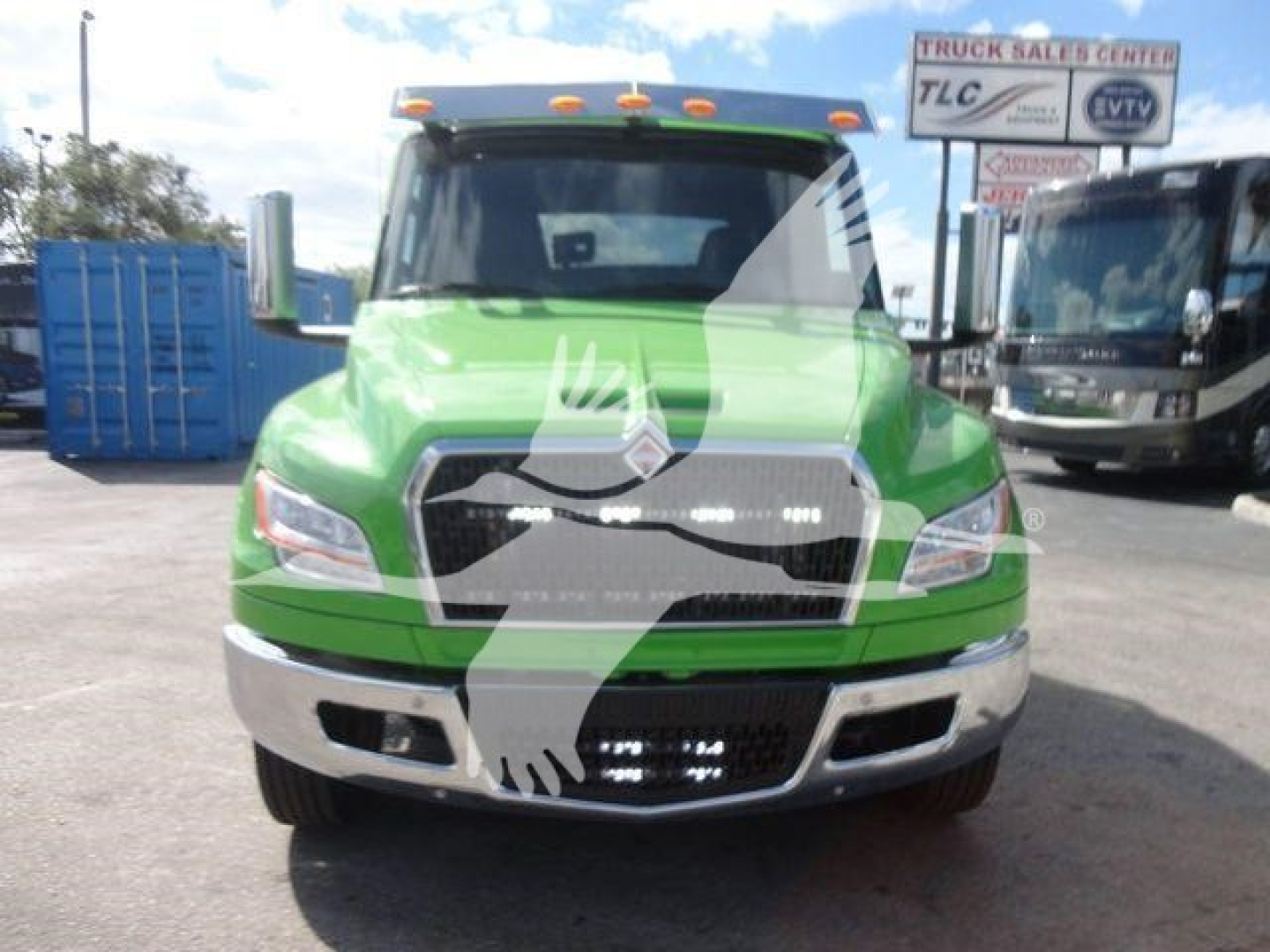 Front view of a green 2027 International MV rollback truck in a dealership lot with other trucks in background.
