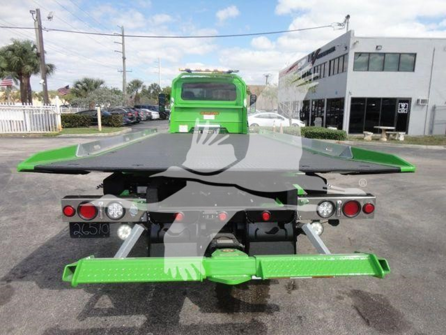 Green International MV rollback tow truck rear view showing lifting bed and tail lights.