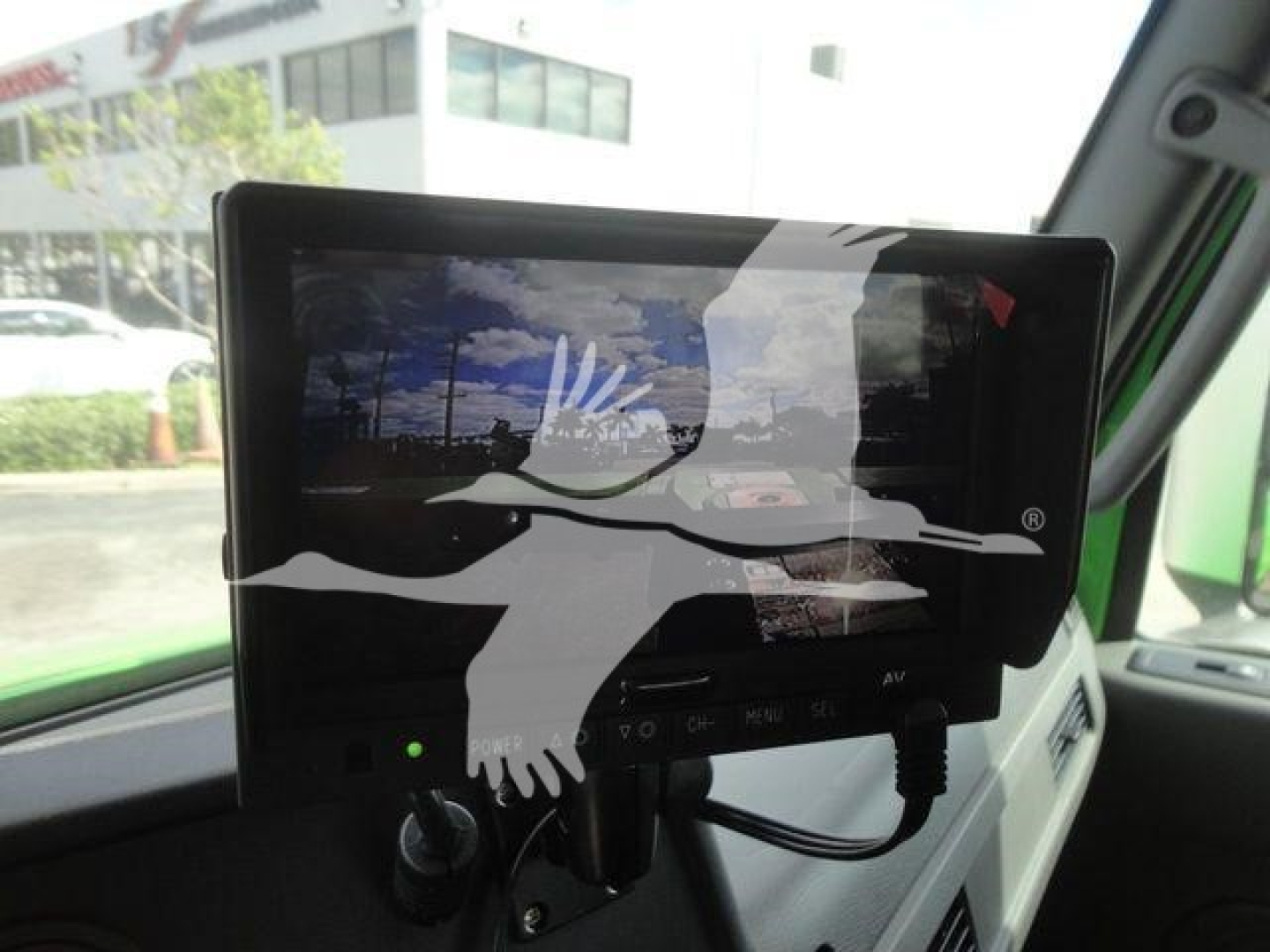 Vehicle dashboard screen mounted on the right with a graphic overlay of a bird in flight and cables visible