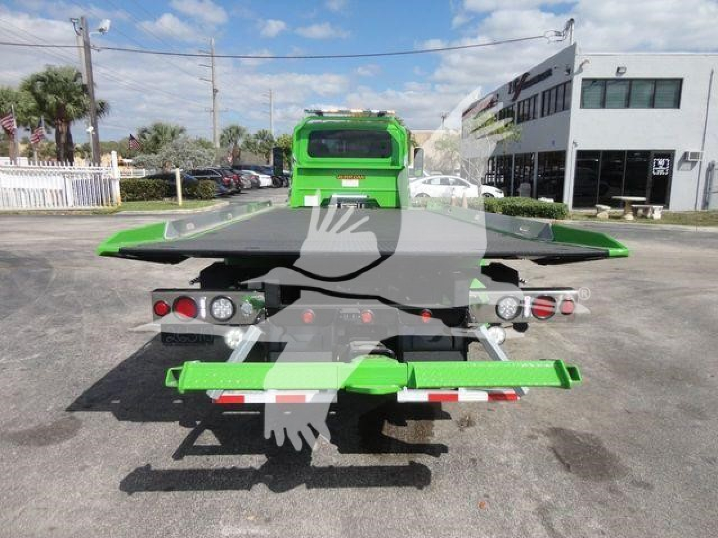 Green International MV tow truck flatbed in-service rear view showing dual taillights and rear equipment.