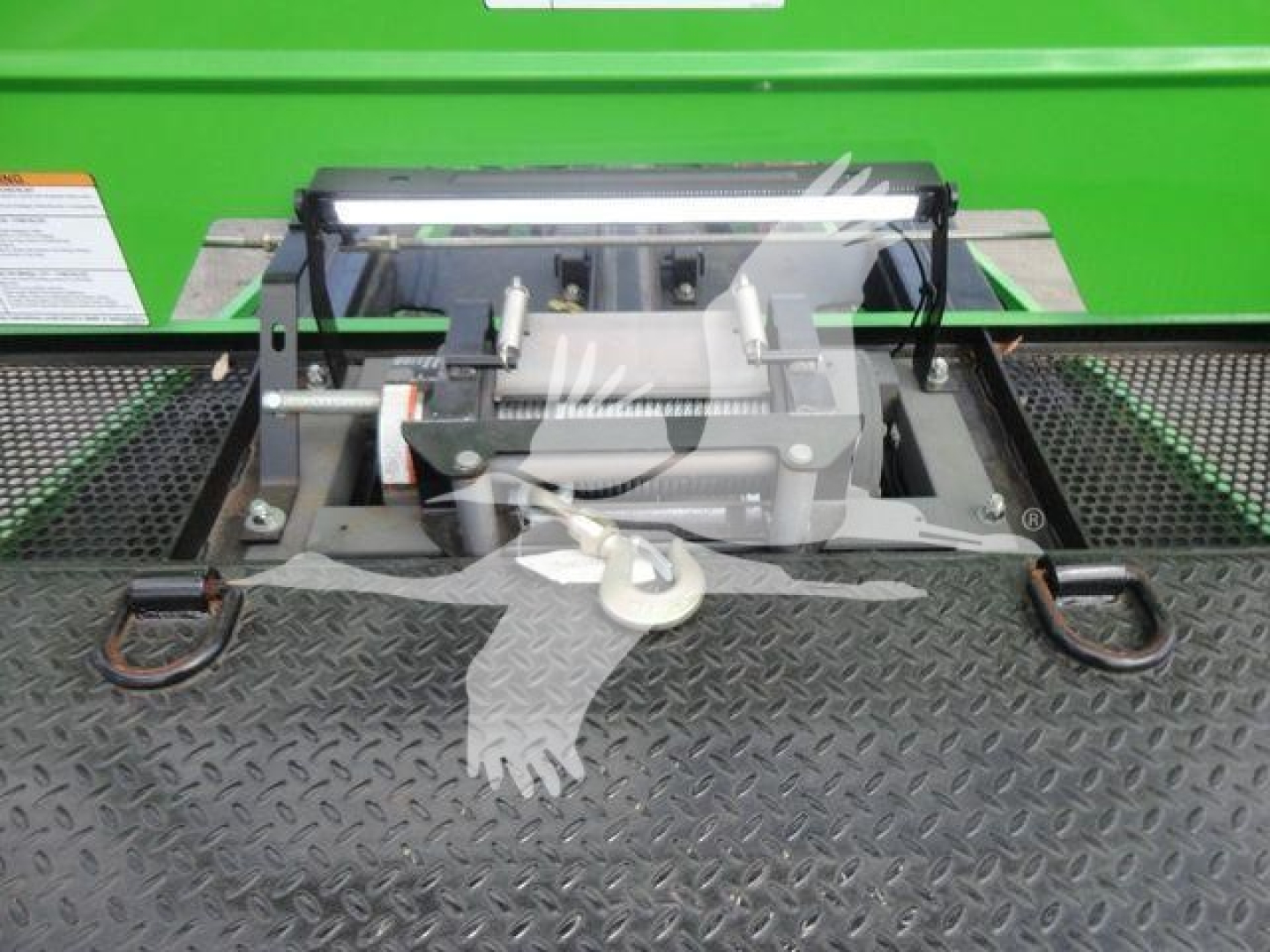 Tractor hitch assembly and front portion of a green rollback truck showing mounting hardware and winch assembly.
