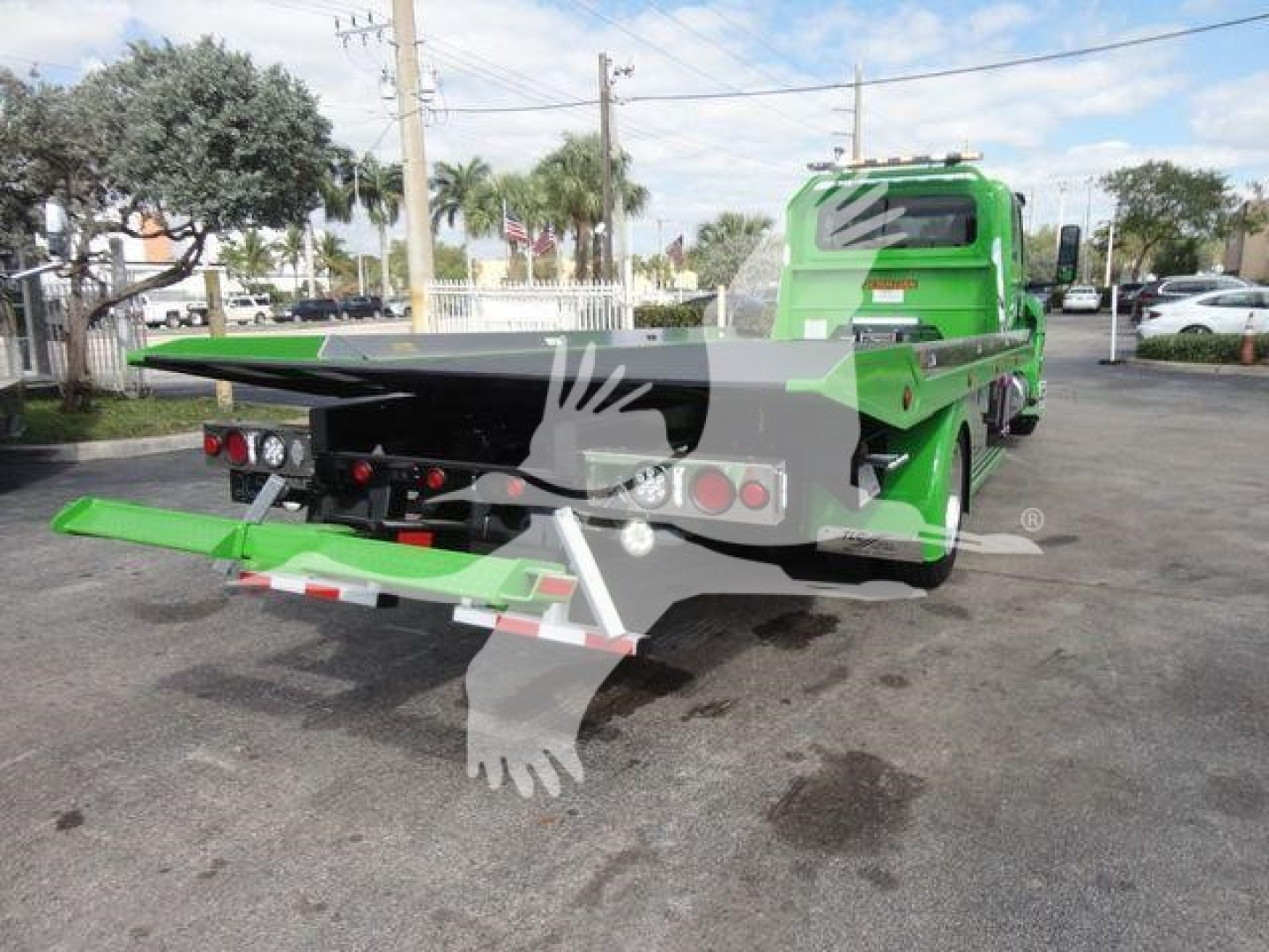 Truck cab in green with a green rollback bed extended, rear view showing loading ramp and license-plate area, MV607STEPSIDEFM stock tag in background