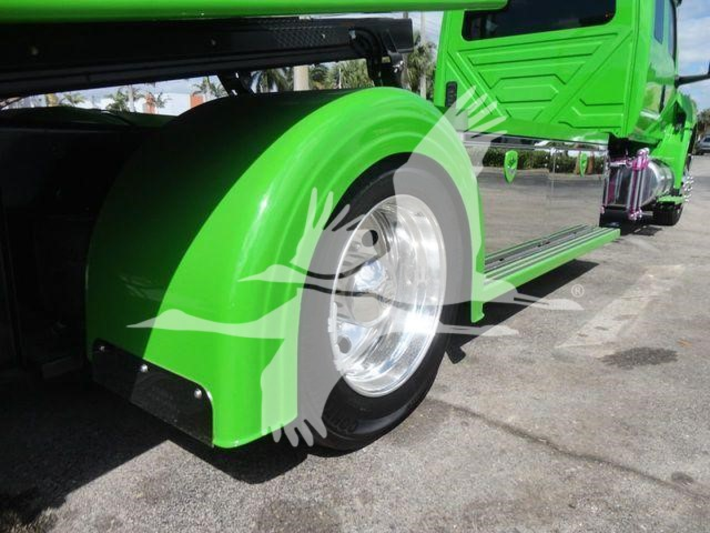 Truck fender and wheel of a bright green International MV rollback truck, chrome wheel, glossy paint, side step visible