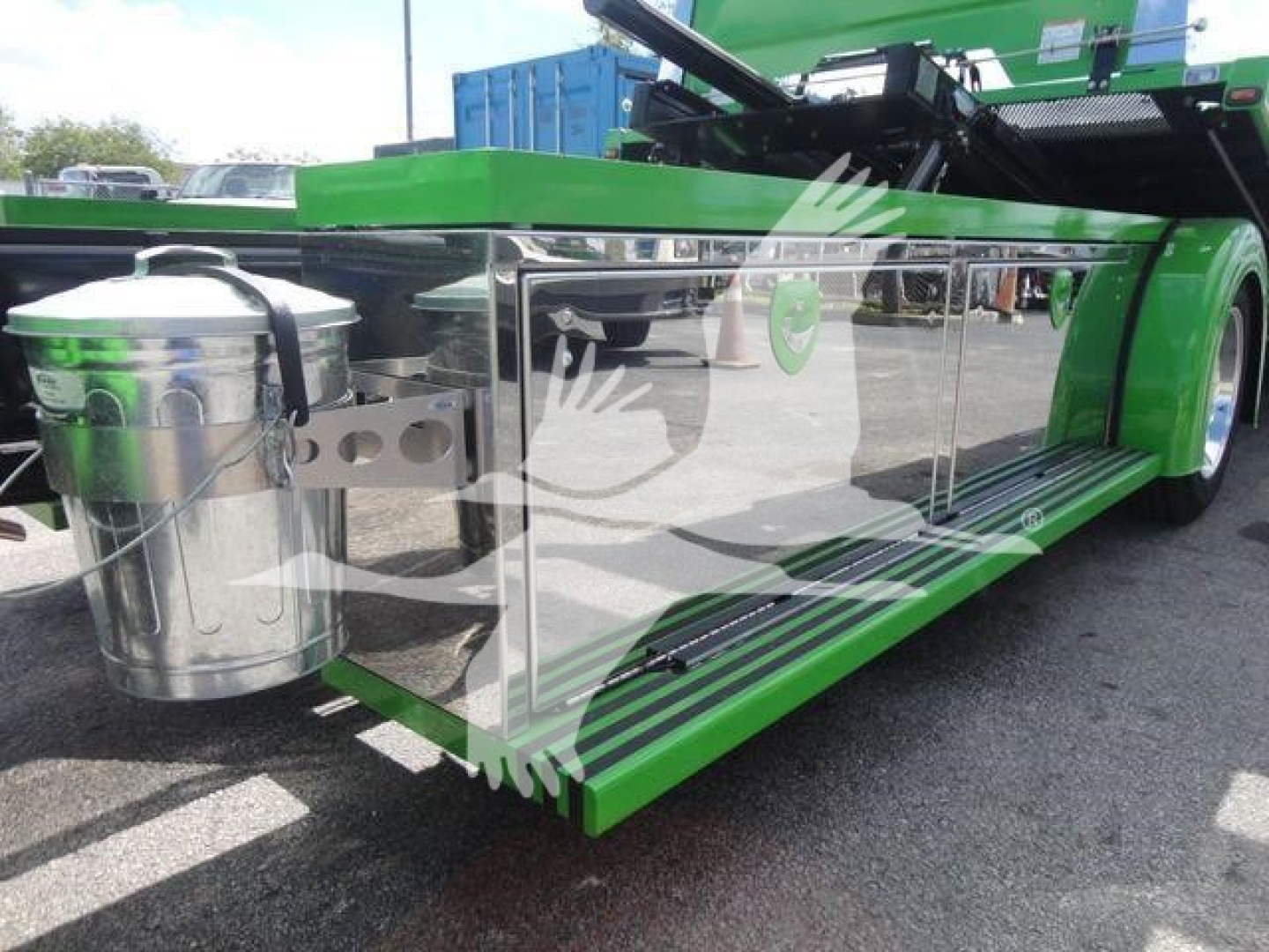 Truck side view showing green International MV rollback truck with chrome side toolbox, fuel tank, and running boards.