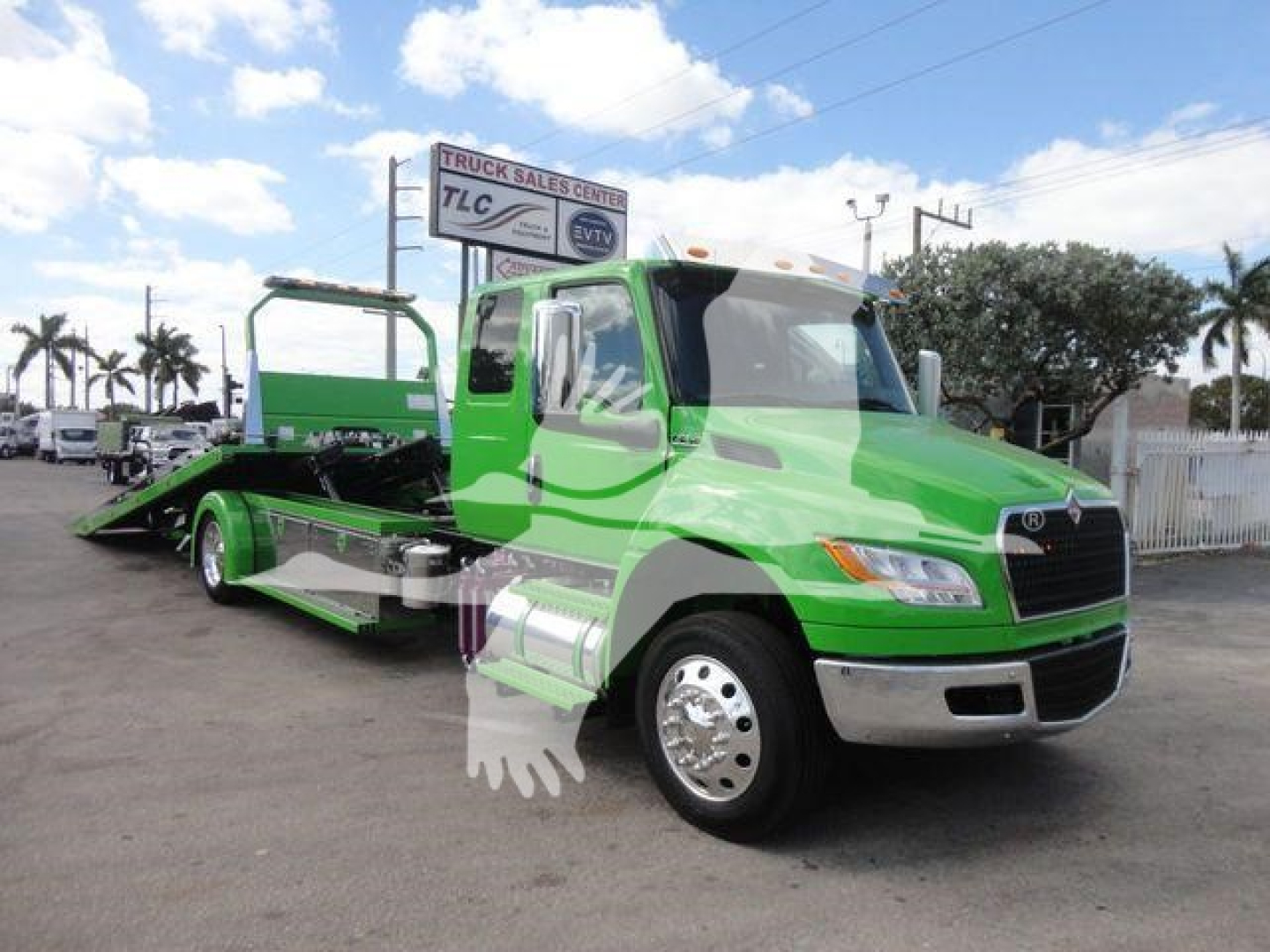 Tow truck in bright green showing MV607Stock International MV model on lot with rollback bed and chrome bumper.