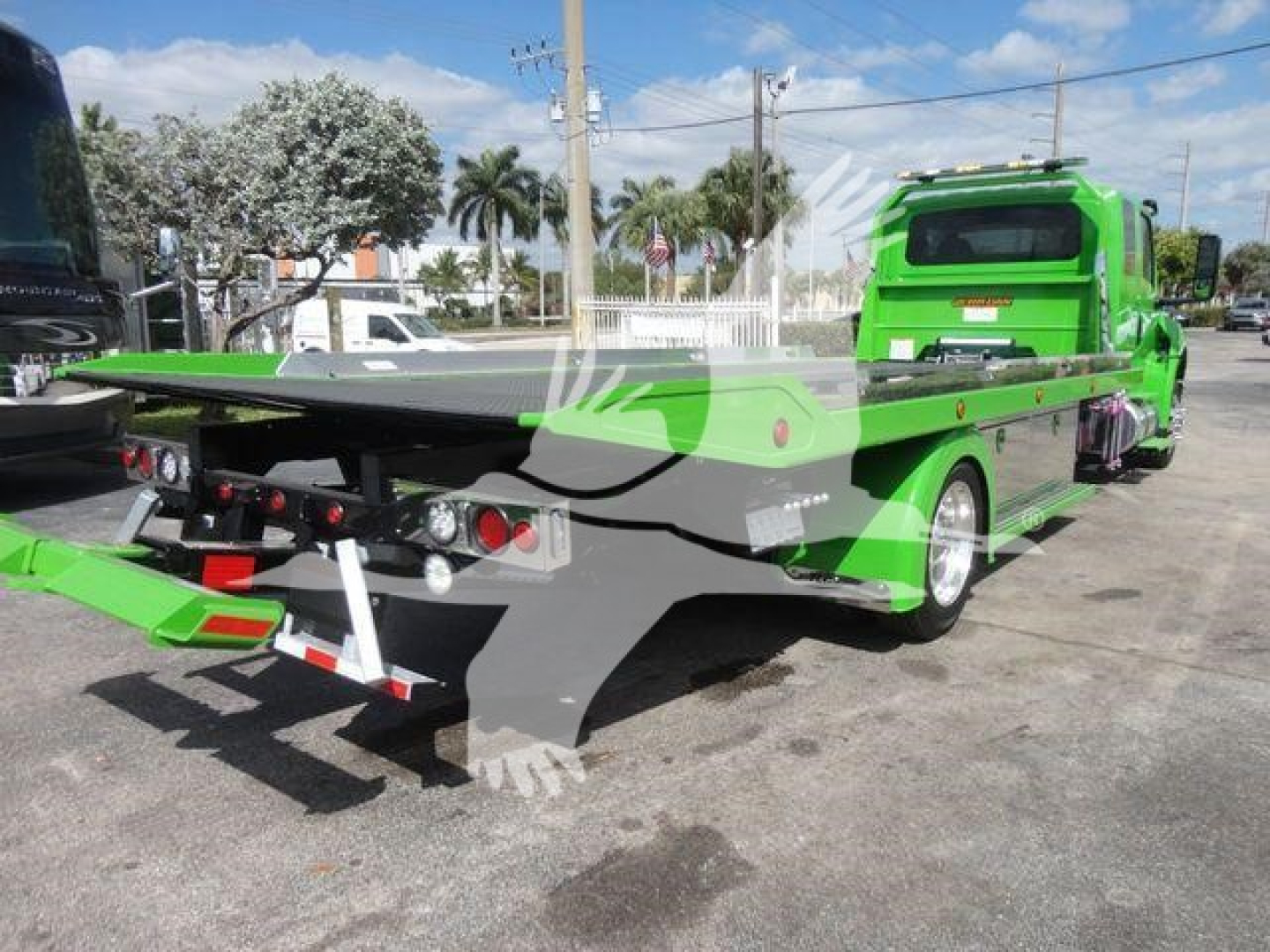 MV607STEPSIDEFM International flatbed tow truck showing bright green color and rollback bed with rear lighting and support winch