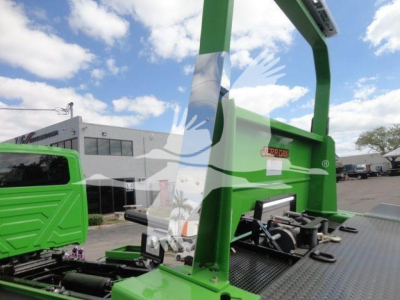 Green International MV rollback truck equipment frame with hydraulic lift and platform, side view showing metal deck and support beams.