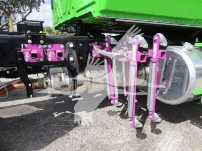 Truck undercarriage showing purple hydraulic components and a silver air tank attached to a green dump body.