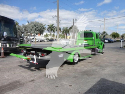 Green tow truck with a flatbed and MV607 stock number visible in lot. Side view shows green cab, chrome wheels, and loading bed.