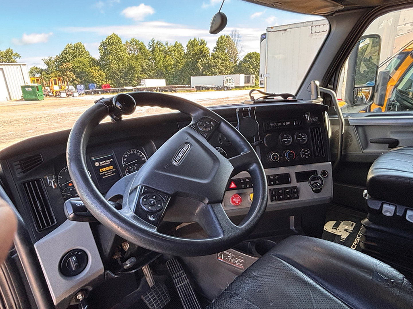 Truck cab interior showing steering wheel and dashboard of a Freightliner Cascadia 2019 with multiple gauges and controls.
