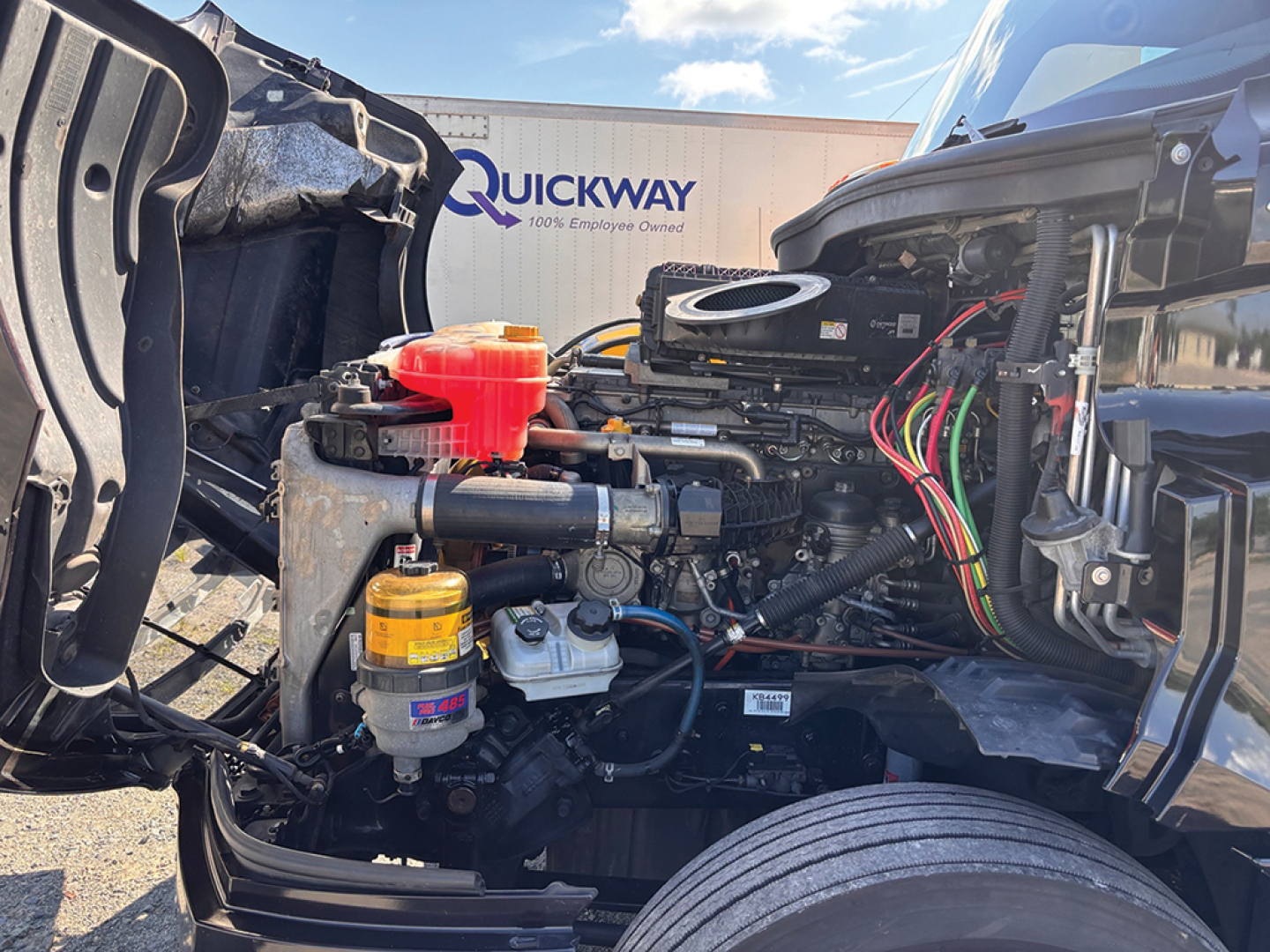 Freightliner Cascadia126 engine bay showing coolant reservoir and air filter assembly with wiring harness in view.