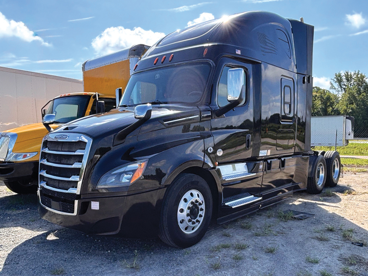 Freightliner Cascadia126 tractor-trailer in dark color with sleeper cab, front view, dual rear axles, chrome bumper and mirrors.