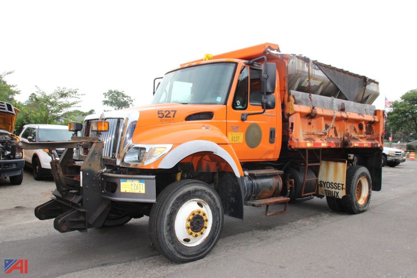 Orange International WorkStar 7400 dump truck with front plow attachment, cab number 527, in-service showing large dump bed and wheel wells.