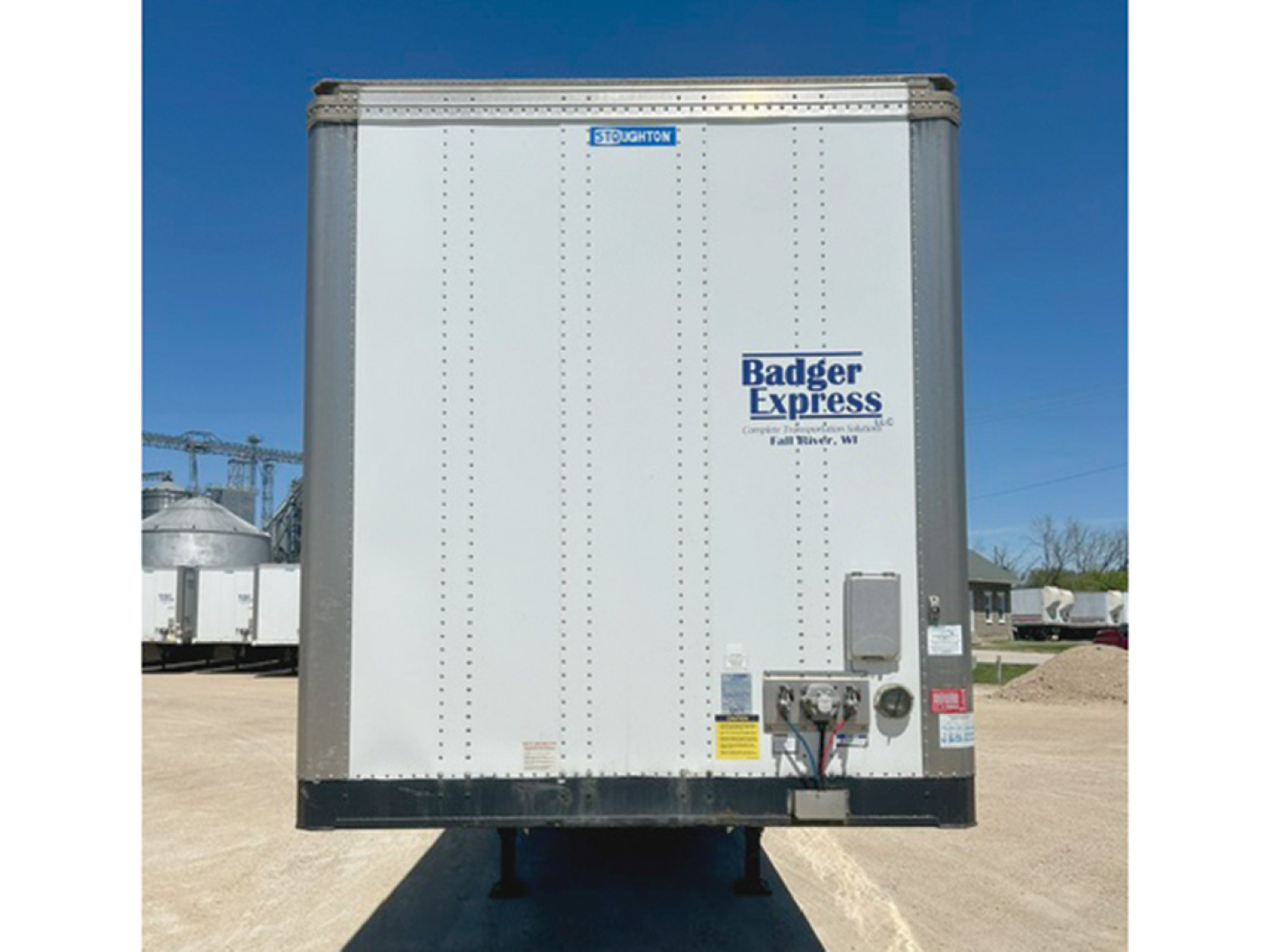 Rear view of a 2018 Stoughton trailer with Badger Express logo on white aluminum door and license plate area, stock number 550061, VIN JS779015.