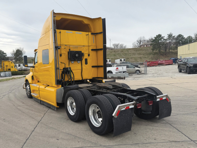 Truck cab and rear chassis of a yellow 2024 International LT625 sleeper cab, dual rear axles, third axle visible, rear mud flaps, displayed in a lot.